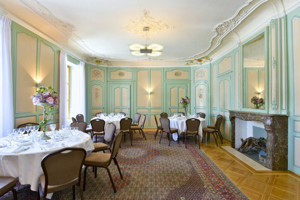 Salle élégante du Vieux Bois à Genève : décoration de style ancien, cheminée et tapis persan.