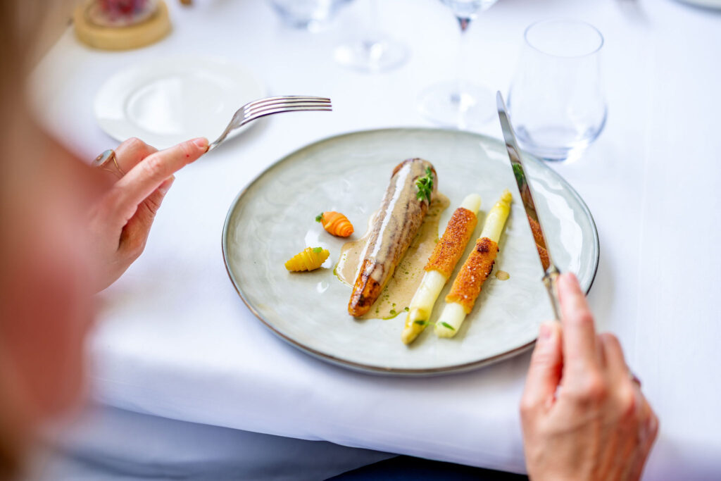 Plat de légumes frais et mains d'un client prêt à déguster au restaurant Vieux Bois à Genève.