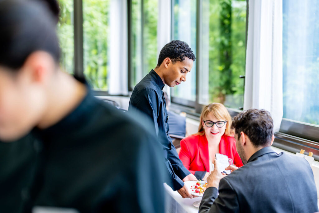 Service à table professionnel au Vieux Bois : étudiant de l'EHG présentant un plat aux clients à Genève.